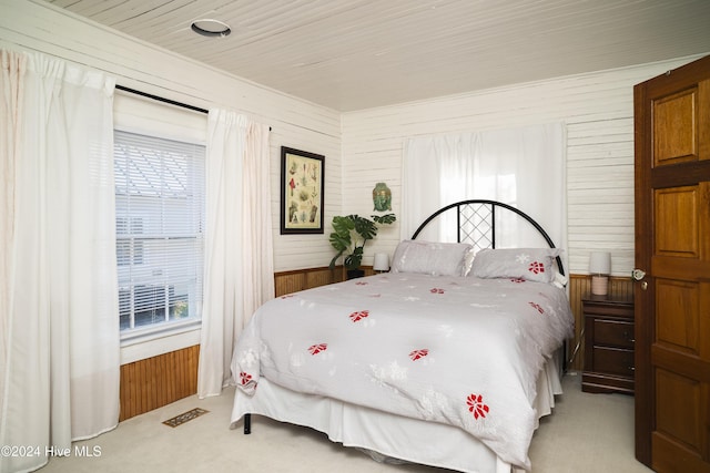 bedroom with multiple windows, light carpet, wooden walls, and visible vents