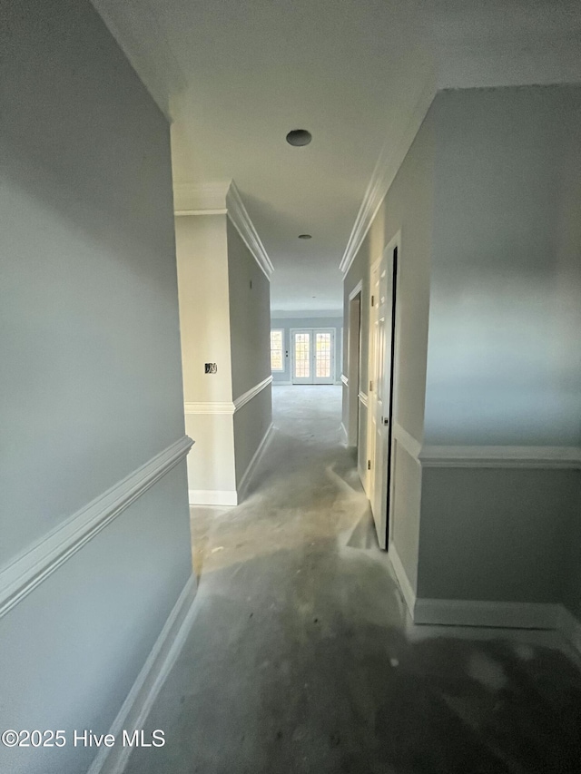 corridor with ornamental molding, concrete floors, and baseboards