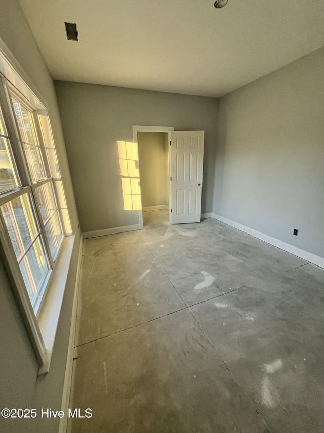 spare room with unfinished concrete flooring and baseboards