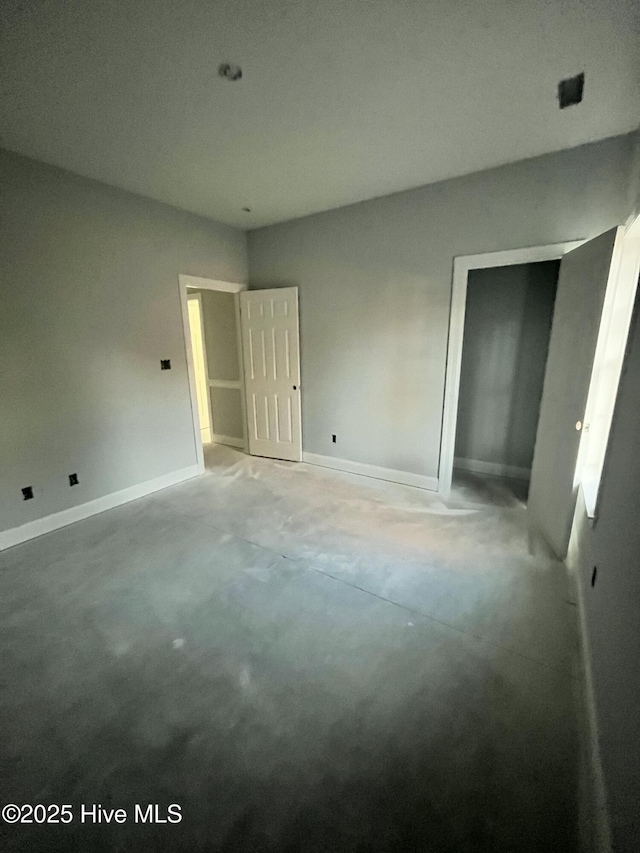 unfurnished bedroom featuring baseboards and unfinished concrete floors