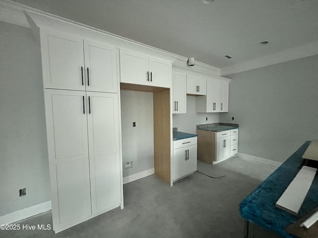 kitchen featuring ornamental molding, white cabinetry, and baseboards