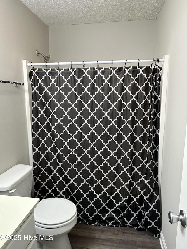 bathroom featuring hardwood / wood-style floors, vanity, toilet, a textured ceiling, and curtained shower