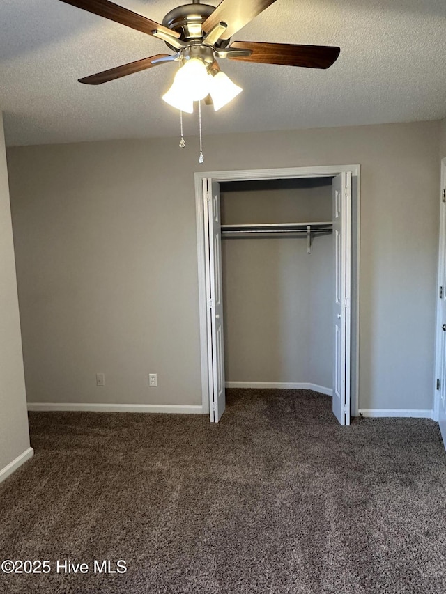 unfurnished bedroom with ceiling fan, a closet, a textured ceiling, and dark colored carpet