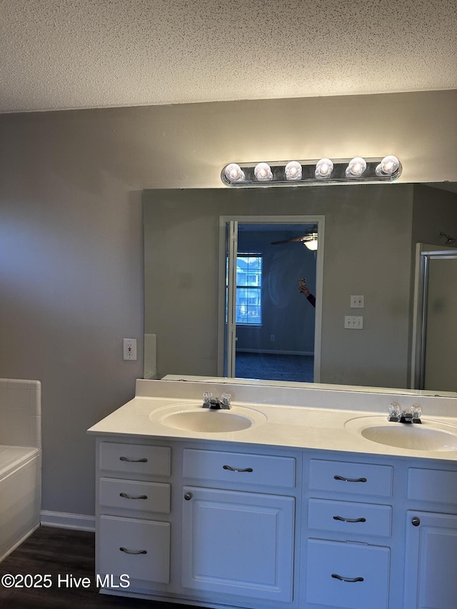 bathroom featuring separate shower and tub, vanity, and a textured ceiling