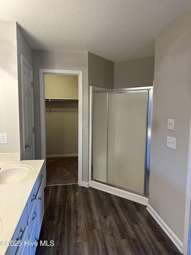 bathroom with vanity, a textured ceiling, hardwood / wood-style flooring, and walk in shower