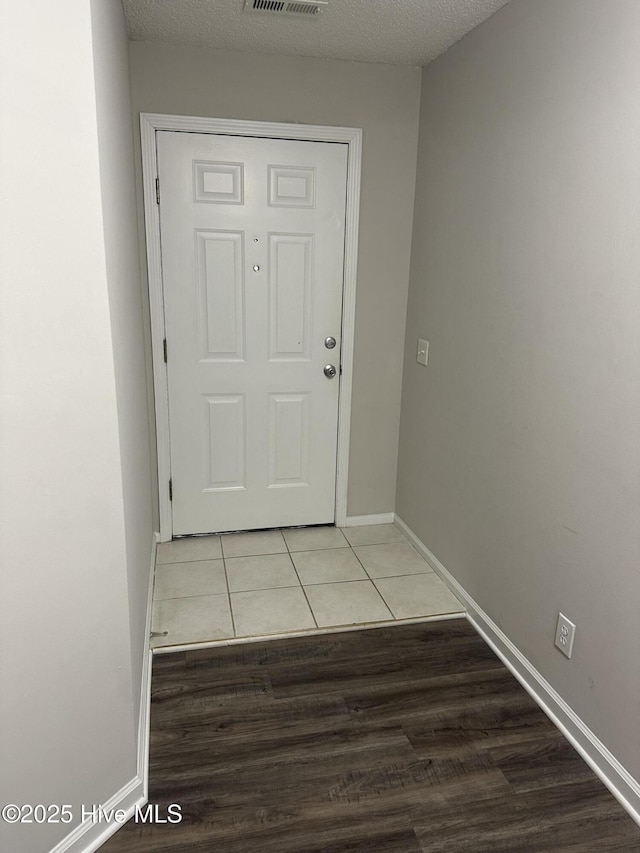 doorway featuring light tile patterned floors and a textured ceiling