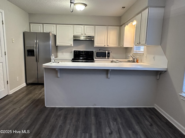 kitchen with dark wood-type flooring, kitchen peninsula, a textured ceiling, appliances with stainless steel finishes, and white cabinetry