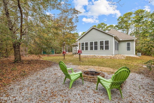 rear view of house featuring a sunroom, a yard, and an outdoor fire pit