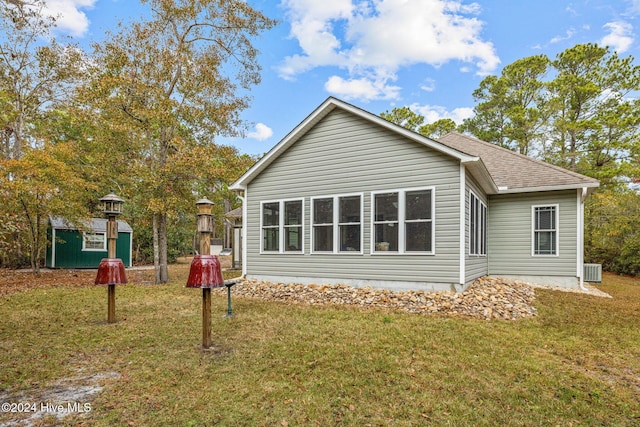 back of property with a yard, cooling unit, and a storage shed