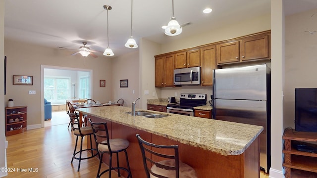 kitchen featuring ceiling fan, sink, stainless steel appliances, a kitchen island with sink, and light wood-type flooring