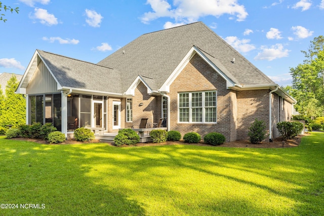 rear view of house with a lawn and a sunroom