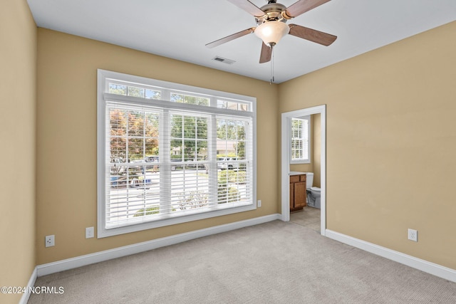 carpeted spare room with ceiling fan and plenty of natural light