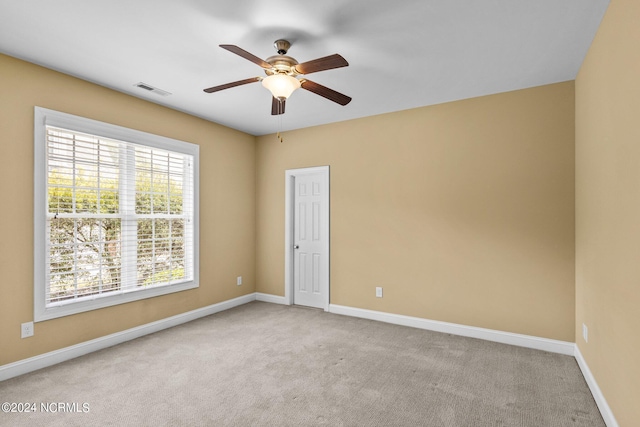 empty room with ceiling fan and light carpet