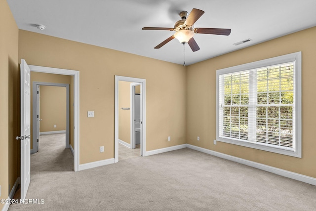 unfurnished bedroom featuring ceiling fan, light colored carpet, and a walk in closet