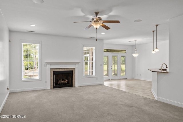 unfurnished living room with ceiling fan, a fireplace, and light colored carpet