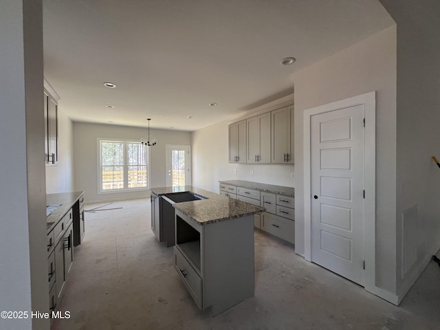 kitchen featuring a center island, black electric stovetop, light stone countertops, decorative light fixtures, and recessed lighting