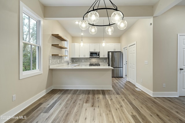 kitchen featuring appliances with stainless steel finishes, white cabinetry, backsplash, decorative light fixtures, and kitchen peninsula