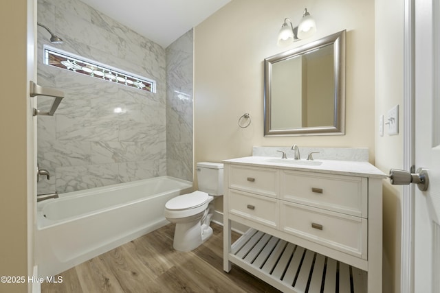 full bathroom with tiled shower / bath, vanity, toilet, and hardwood / wood-style floors