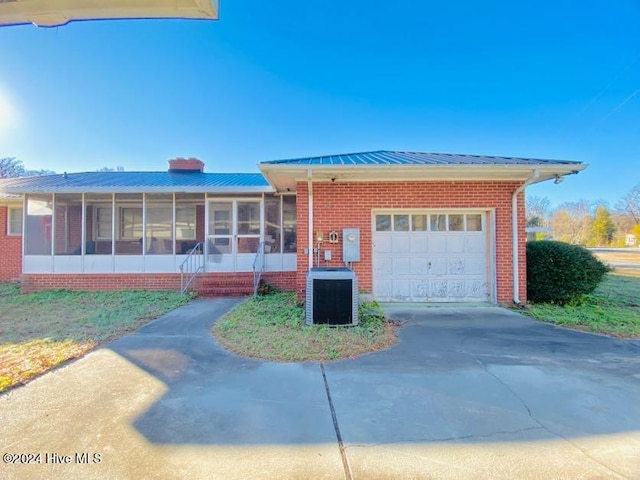 view of front of house with a garage, cooling unit, and a sunroom