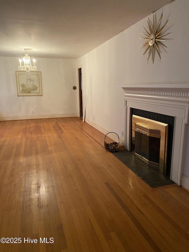 unfurnished living room featuring an inviting chandelier and hardwood / wood-style flooring