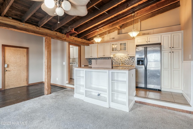 kitchen with washer / clothes dryer, lofted ceiling with beams, hanging light fixtures, light colored carpet, and stainless steel fridge with ice dispenser