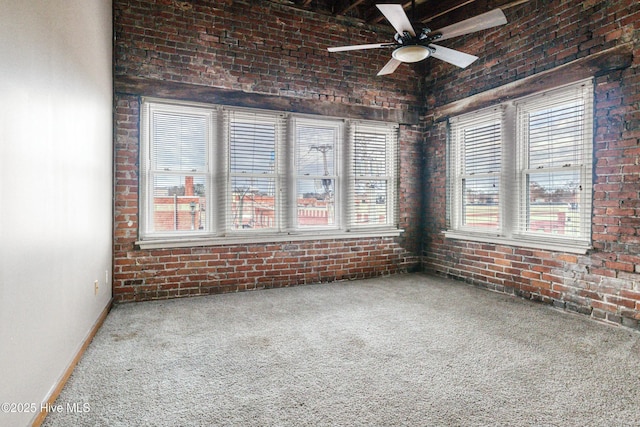 carpeted spare room featuring brick wall and ceiling fan