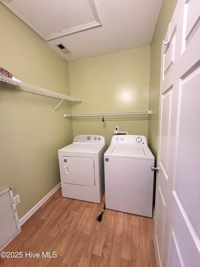 laundry room with independent washer and dryer, a textured ceiling, and light hardwood / wood-style flooring