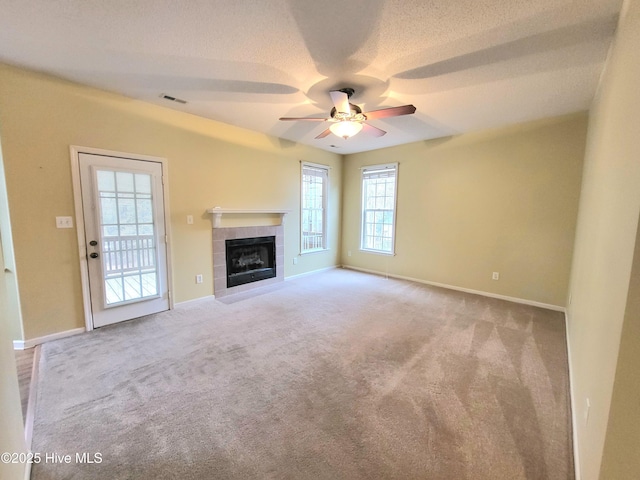 unfurnished living room featuring ceiling fan, a fireplace, light carpet, and a textured ceiling