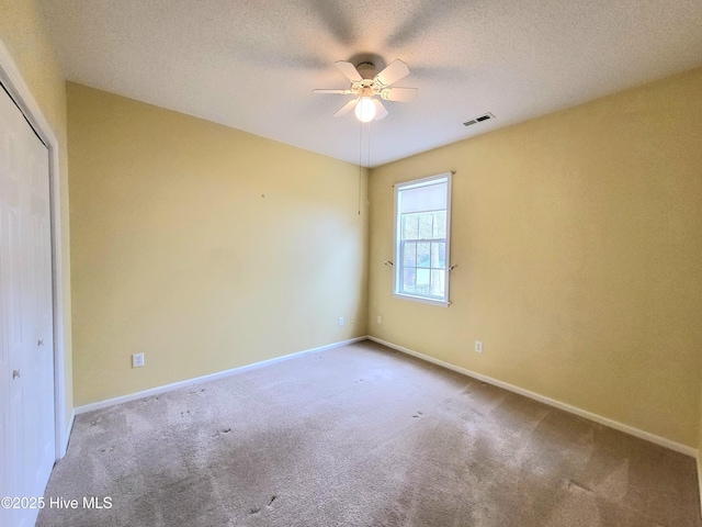 carpeted spare room featuring ceiling fan and a textured ceiling