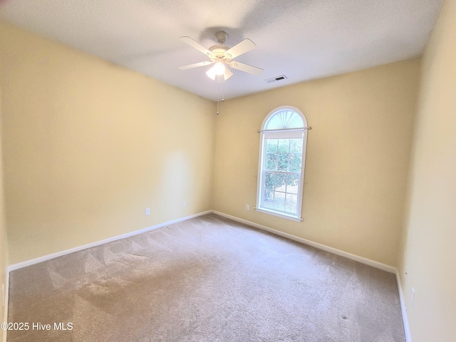 carpeted spare room featuring ceiling fan and a textured ceiling