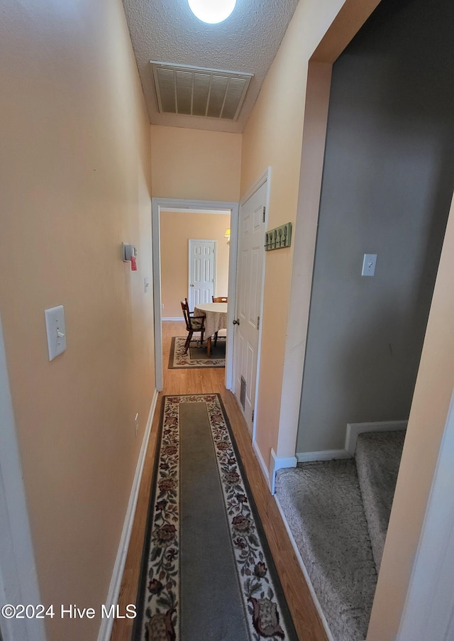 hall featuring a textured ceiling and hardwood / wood-style flooring