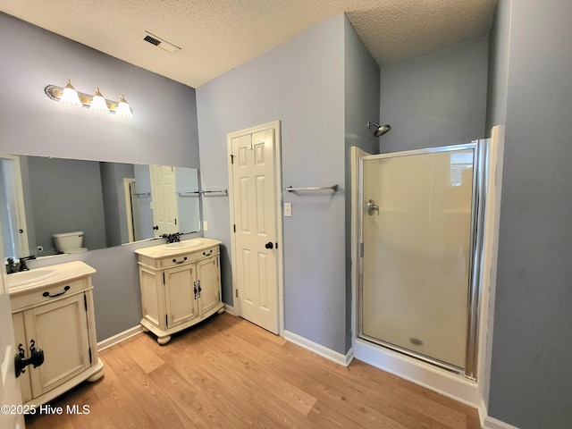 bathroom featuring hardwood / wood-style floors, vanity, a shower with door, and a textured ceiling