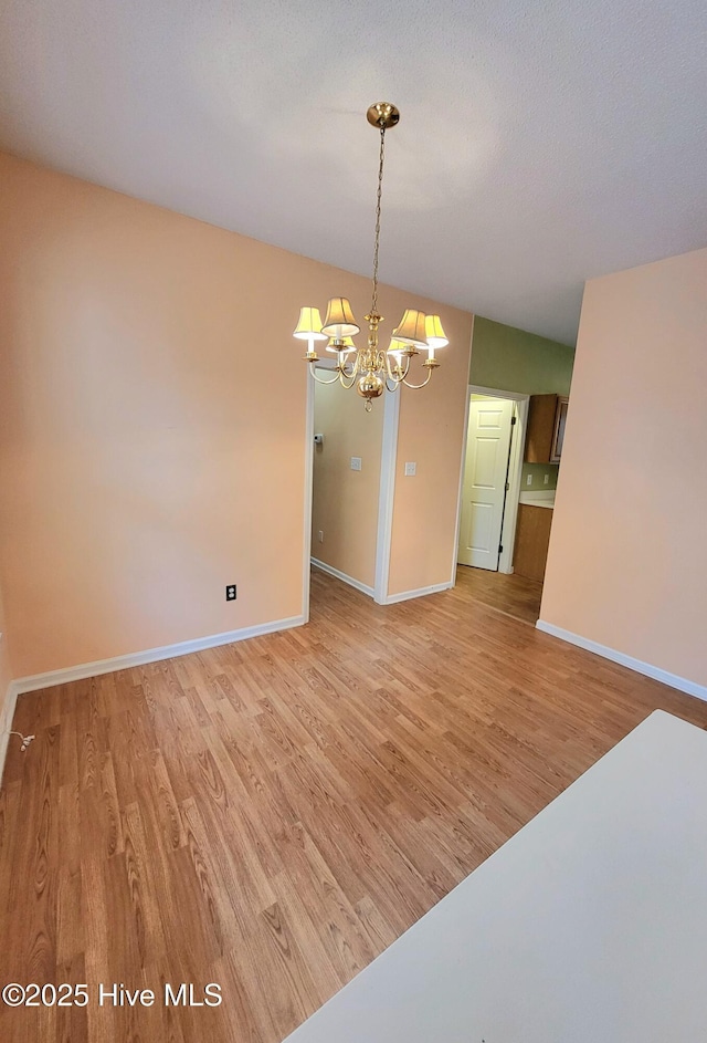 spare room featuring wood-type flooring and an inviting chandelier