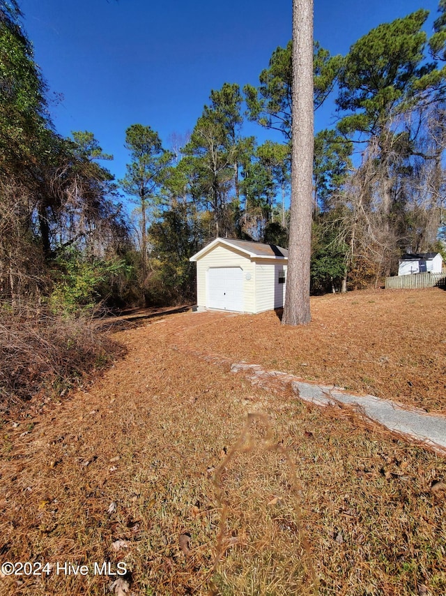 view of yard with a garage and an outbuilding