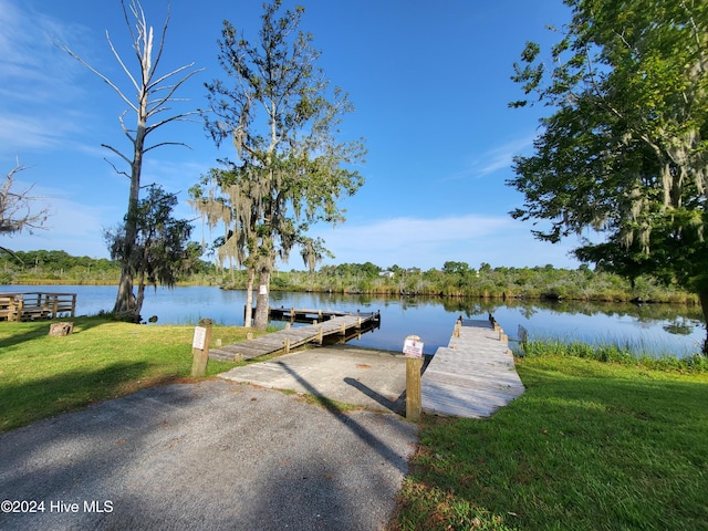 view of dock featuring a lawn and a water view