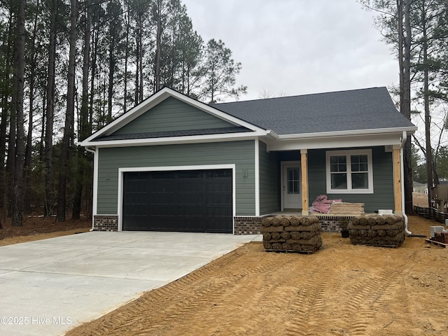 view of front facade with brick siding, roof with shingles, covered porch, concrete driveway, and a garage