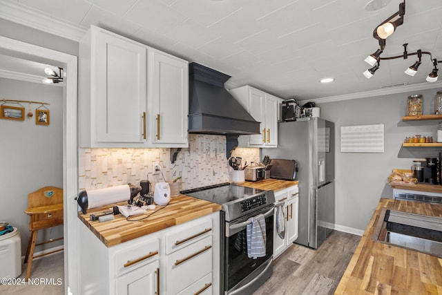 kitchen featuring appliances with stainless steel finishes, premium range hood, crown molding, white cabinetry, and butcher block counters