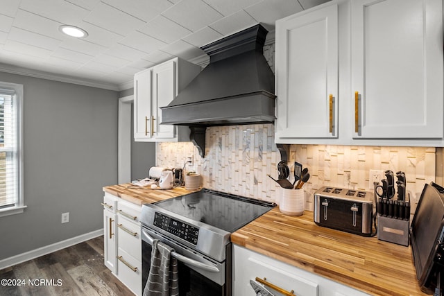 kitchen with white cabinetry, stainless steel range, dark hardwood / wood-style floors, premium range hood, and ornamental molding