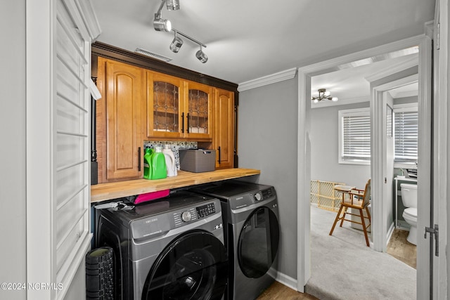 washroom featuring cabinets, washing machine and dryer, crown molding, track lighting, and light carpet