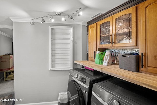 clothes washing area with cabinets, washing machine and dryer, and ornamental molding