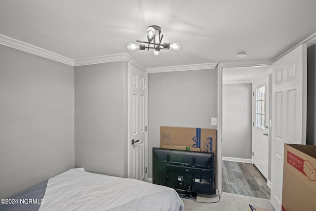 bedroom with crown molding, hardwood / wood-style floors, and a notable chandelier