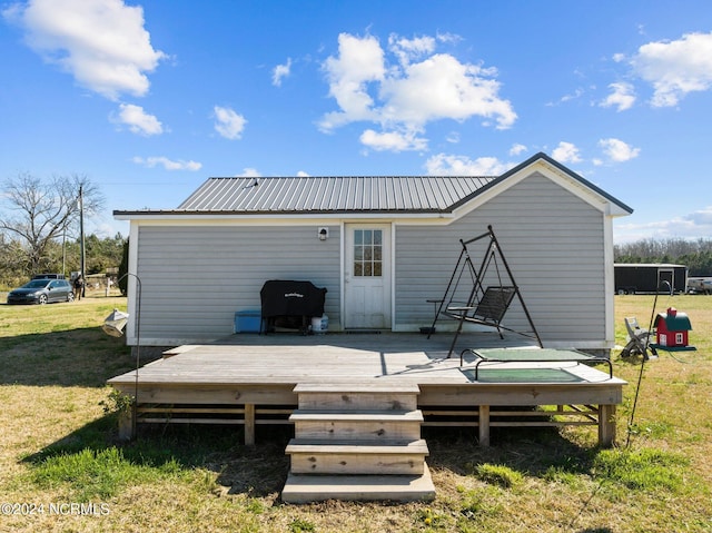 back of house featuring a lawn and a wooden deck