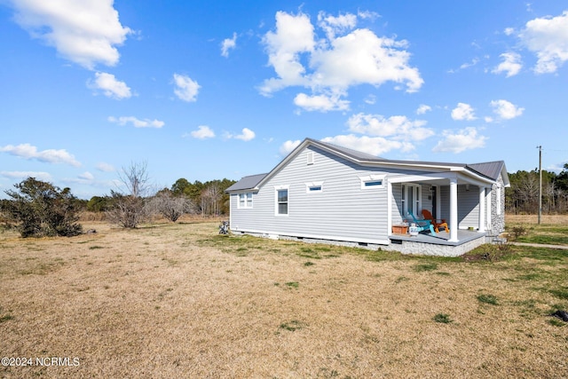 rear view of property featuring a lawn and covered porch