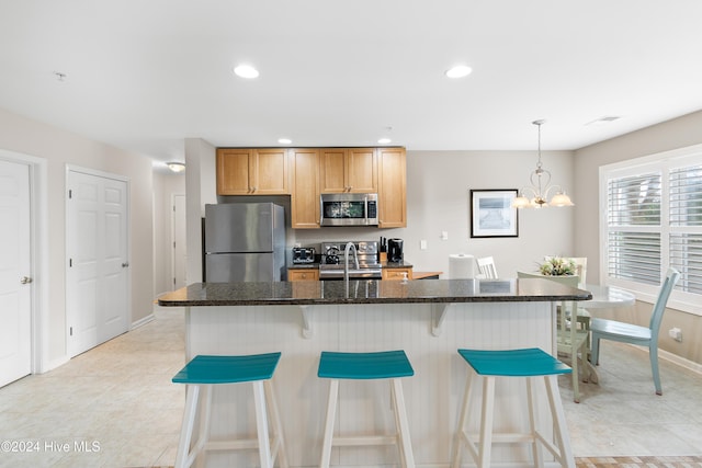 kitchen featuring a kitchen island with sink, stainless steel appliances, hanging light fixtures, and a chandelier