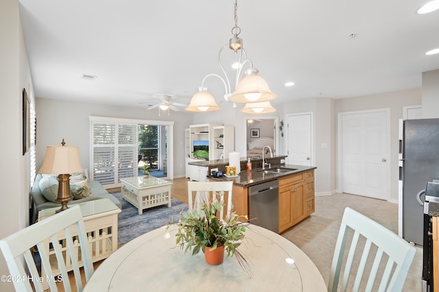 dining space featuring ceiling fan with notable chandelier and sink