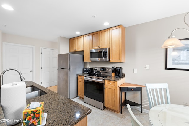 kitchen with sink, dark stone countertops, light brown cabinetry, light tile patterned floors, and appliances with stainless steel finishes