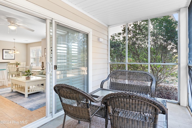 sunroom featuring ceiling fan with notable chandelier