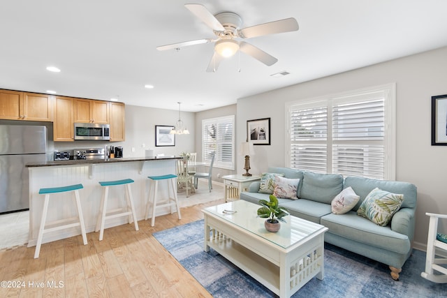 living room featuring light hardwood / wood-style flooring and ceiling fan with notable chandelier