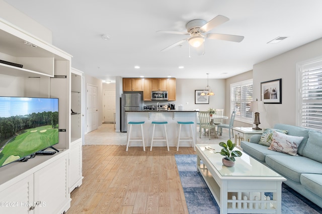 living room featuring light hardwood / wood-style floors and ceiling fan with notable chandelier