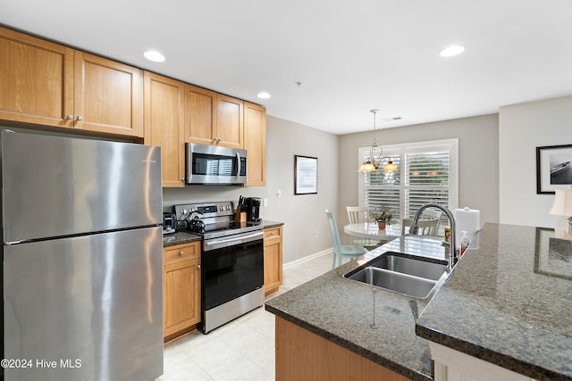 kitchen featuring sink, hanging light fixtures, an inviting chandelier, dark stone counters, and appliances with stainless steel finishes